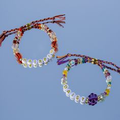 two bracelets with beads and tassels are shown against a blue sky background