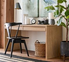 a wooden desk topped with a black chair next to a potted plant