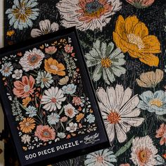 two puzzles are sitting on top of each other in front of a black background with colorful flowers