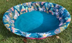 a dog bed in the grass with butterflies on it and a blue cushion inside that has been made to look like a butterfly print