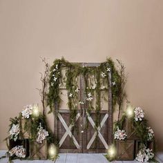 an arrangement of flowers and greenery is displayed in front of a rustic wooden gate