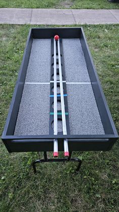 an outdoor table tennis game on the grass with two red and white sticks sticking out of it