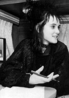 a black and white photo of a woman sitting on a train holding a cell phone