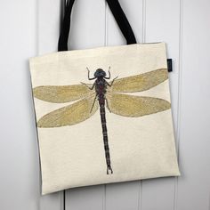 a tote bag with a drawing of a dragonfly on it hanging from a door