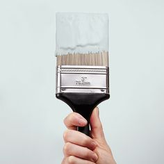 a hand holding a paint brush with white bristles