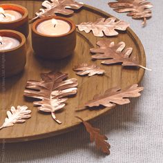 three candles on a wooden tray with leaves