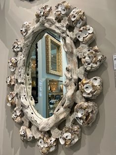 there is a mirror made out of driftwood and shells on the wall next to it