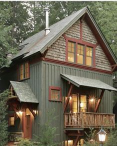 a small house with lots of windows and lights on the front porch, surrounded by trees