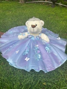 a teddy bear in a dress laying on the grass