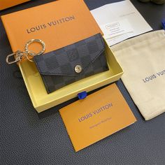 the louis vuitton wallet and keychain are on display in front of an open box