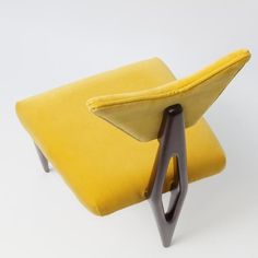 a yellow chair sitting on top of a white floor next to a wooden legrest