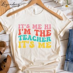 𝙏-𝙎𝙝𝙞𝙧𝙩: It's Me Hi I'm The Teacher It's Me Design is made on a Cotton Unisex T-Shirt. Perfect for the first day of school or to get your students to smile! Size up for the popular oversized look. 𝗜𝗺𝗽𝗼𝗿𝘁𝗮𝗻𝘁 𝗧𝗶𝗱 𝗕𝗶𝘁𝘀: ✏️ Orders ship in 1-2 business days. ✏️ Need your item sooner? Upgrade to Priority Mail Express at checkout. ✏️  Size charts are available for all styles. ✏️  Colors may vary depending on your computer screen. ✏️  Machine wash cold inside out & tumble dry low. Its Me Hi Im The Teacher Its Me, Vintage Cotton T-shirt With Funny Text, Funny Slogan T-shirt For Teacher Appreciation, Fun Graphic Print T-shirt For Teacher Appreciation, Fun Teacher Appreciation T-shirt With Graphic Print, Retro Crew Neck T-shirt For Teacher Appreciation, Graphic Tee With Screen Print For Teacher Appreciation, Graphic Tee With Slogan For Teacher Appreciation, Graphic Tee Shirt With Slogan For Teacher Appreciation