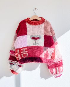 a pink and red sweater hanging on a white wall