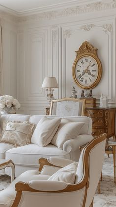 a living room filled with white furniture and a large clock on the wall above it