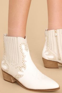 These exclusive Wild West Wonder Ivory Boots combine upscale style with rustic charm. Their intricate Western embroidery, refined stitching, and sturdy construction create a luxurious look that's perfect for your style statement. Step into the Wild West with these timeless boots, crafted with sophistication and luxury in mind. These ankle boots feature a pointed toe, a side zipper closure, a stretchy side panel, embroidered detailing, and a stacked heel. • Heel measures 2" • Man Made Materials • Cream Western Boots For Fall, Western Cream Ankle Boots, Western Style Cream Ankle Boots, Western Cream Snip Toe Heeled Boots, Western Cream Heeled Boots With Snip Toe, Western Cream Heeled Boots With Round Toe, White Western Ankle Heeled Boots, Western Cream Heeled Boots For Spring, Western Cream Pointed Toe Heeled Boots