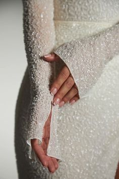 the back of a woman's white dress with sequins on her arms