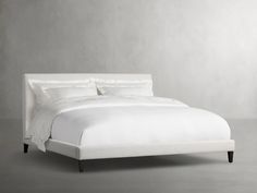 a bed with white sheets and pillows in a room