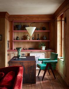 a living room with wood paneling and red couches in front of wooden shelves