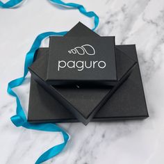 two black boxes with the words on them are sitting on a marble surface and blue ribbon