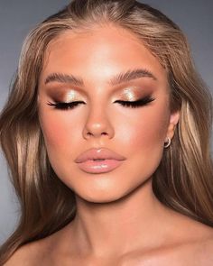 a woman with long blonde hair and gold eyeshadow is shown in front of a gray background