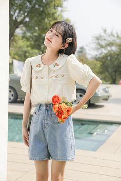 Button up shirt with a peter pan collar, short puff sleeves and embroidered orange flowers on the collar and chest. S: 13.5" across shoulders, 35" chest, 21" lengthM: 14" across shoulders, 36.5" chest, 21" lengthL: 14.5" across shoulders, 38" chest, 21" length