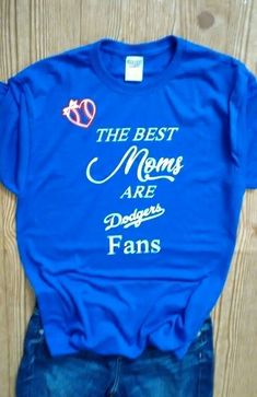 the best moms are dodgers fans t - shirt and jeans on display in front of a wooden wall