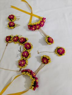 three pieces of yellow and pink beaded jewelry on a white tablecloth with ribbon