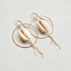 "Beautiful sliced cowrie shells hang within gold filled hammered hoops and have delicate gold chains dangling from them. Hoops measure approximately 1 1/2\". Each cowrie shell is unique so please allow for variations." Handmade Gold Hoop Earrings For Beach, Handmade Gold Hoop Earrings For Vacation, Handmade 14k Gold Filled Beach Earrings, Handmade 14k Gold Filled Earrings For Beach, Beachy Gold Dangle Earrings, Handmade 14k Gold-filled Earrings For Beach, Gold Small Hoop Jewelry For The Beach, Handmade 14k Gold Filled Jewelry For The Beach, Gold Shell-shaped Hoop Earrings For Beach