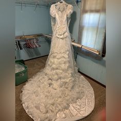 a white wedding dress is on display in a room with clothes hanging from the ceiling