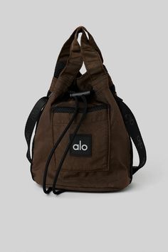 Cross Body Bucket Bag - Espresso/Black | Alo Yoga Functional Bucket Bag For On-the-go, Brown Nylon Bag With Adjustable Strap, Utility Bags With Removable Pouch For Outdoor, Large Capacity Nylon Drawstring Bag For Everyday Use, Functional Crossbody Bucket Bag For Daily Use, Functional Pouch Bucket Bag For Travel, Brown Utility Bag For Daily Use, Functional Pouch-style Bucket Bag For Travel, Functional Rectangular Bucket Bag For On-the-go