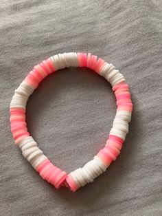 a pink and white bracelet on top of a bed