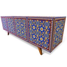 an ornately decorated sideboard with wooden legs and colorful tiles on the top, against a white background