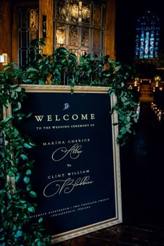 a welcome sign is surrounded by greenery and candles in front of a church door