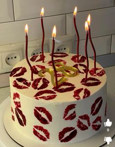 a white cake with red lipstick on it and candles in the shape of lips is shown