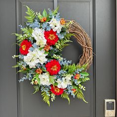 a wreath with red, white and blue flowers hanging on a door