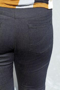 the back view of a woman's jeans with her hand in her pocket and an orange striped shirt