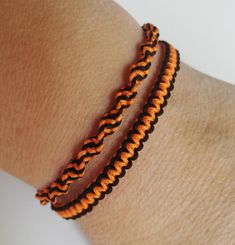 an orange and black bracelet is on someone's arm while they both wear it