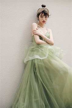 a woman in a green dress leaning against a wall