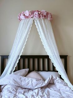 a bed with white sheets and pink flowers on the headboard, hanging above it