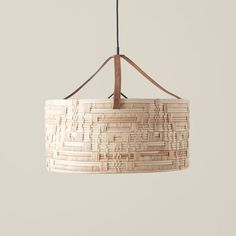 a light fixture made out of woven material hanging from a ceiling lamp holder with leather cord