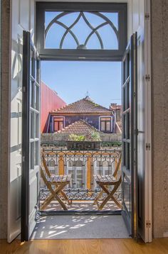 an open door leading to a balcony with chairs