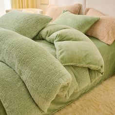 a bed with green comforters and pillows on it