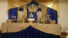 a table topped with a cake covered in gold and blue frosting next to curtains