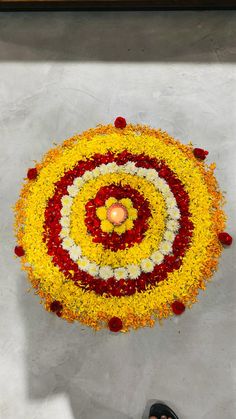 a person standing in front of a flower arrangement with a candle on the floor next to it