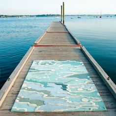 a long dock with an area rug on the water's edge that looks like it has been painted