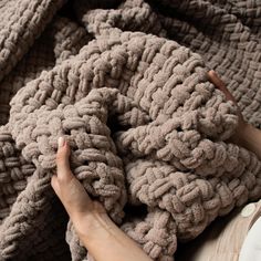 a woman is laying down with her hand on the blanket