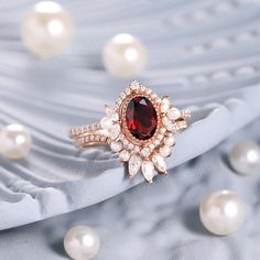 a close up view of a ring with pearls and garnets around it on a blue cloth