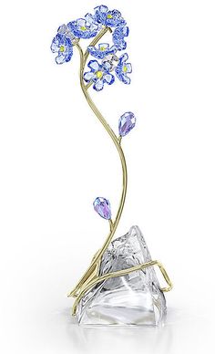 Crafted with meticulous skill, this stunning creation captures the beauty of one of nature’s most eye-catching flowers. The blue forget-me-not is produced with 876 light-catching facets, displayed atop a gold-tone metal stem that gracefully entwines across a natural unfaceted crystal base. Representing true love and faithfulness, this freestanding design would make a truly impressive gift for a loved one, serving as a permanent reminder that they’re in your thoughts. No vase or base required. De Forget Me Not Blue, Forget Me Not Flower, Trending Engagement Rings, Engagement Rings Bridal Sets, Crystal Figurines, Crystal Art, Crystal Collection, Forget Me Not, Gemstone Bracelets