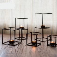 four candles are placed in square metal containers on a wooden table with the words juhan written above them