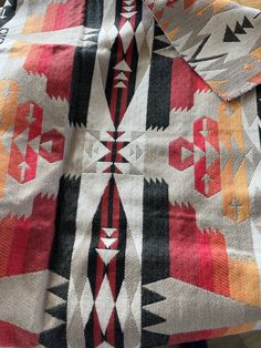 an orange, black, and white blanket with designs on it